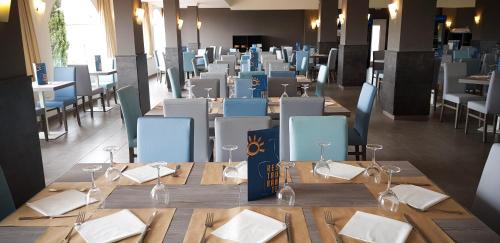 a dining room with wooden tables with wine glasses at Ohtels San Salvador in Comarruga