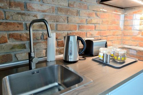 a kitchen counter with a sink next to a brick wall at Bułgarska 59A- (1/2) piękny widok 14 piętro in Poznań