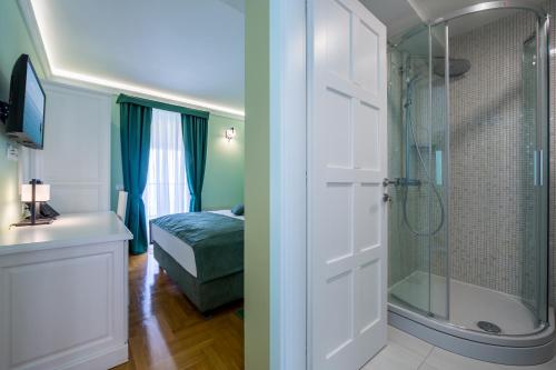 a bathroom with a shower and a bedroom at Hotel Domino in Opatija