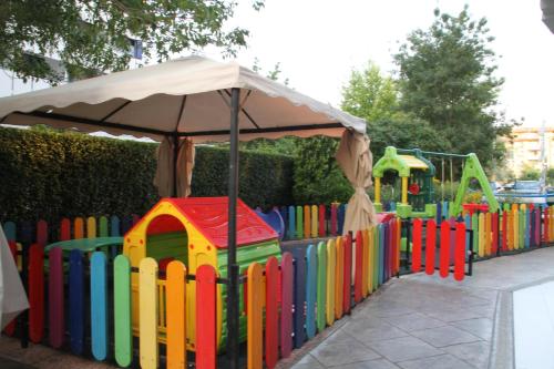 a colorful playground with an umbrella next to a fence at Smartline Meridian Hotel in Sunny Beach