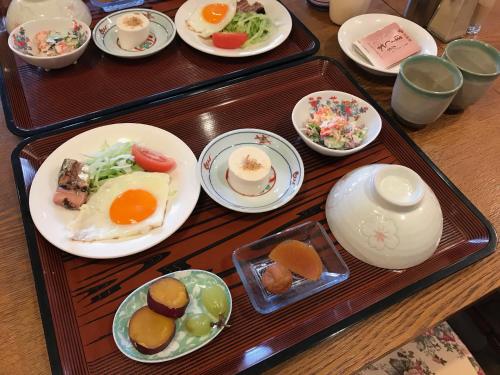 una mesa con dos bandejas de comida. en Kakunodate Guesthouse Fuga en Senboku