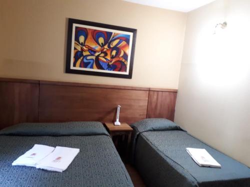 a room with two beds and a painting on the wall at Pousada Raio de Sol in Jaguarão