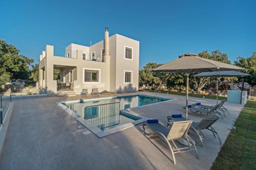 a house with a swimming pool with chairs and an umbrella at Chloe in Vederoi