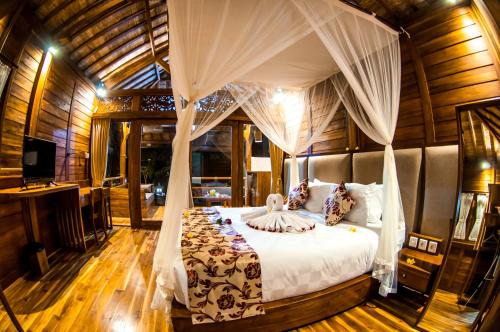 1 dormitorio con 1 cama con dosel en Puri Kobot, en Ubud