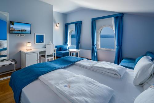 a blue bedroom with a large bed and a desk at Hotel Domino in Opatija