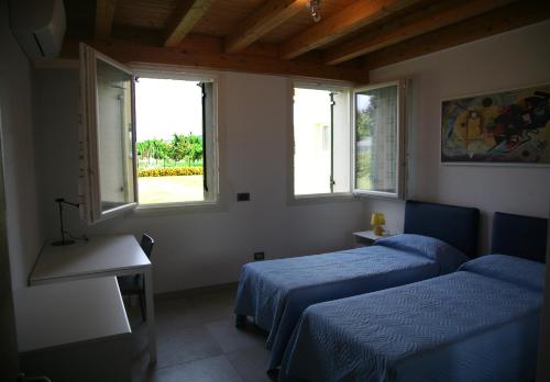two beds in a room with two windows at Ca' Vittori in Valeggio sul Mincio