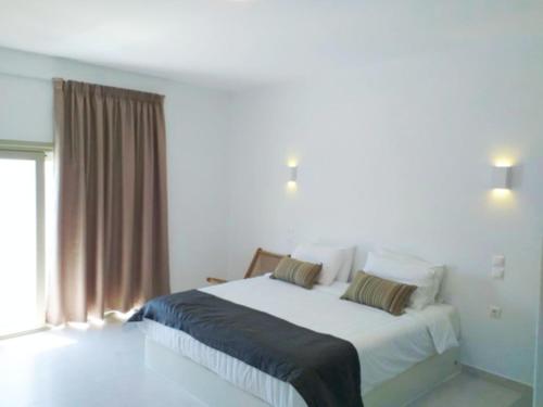 a bedroom with a large white bed with a window at Smaro Studios in Firostefani