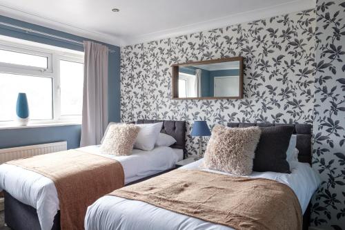 a bedroom with two beds and a mirror on the wall at Modern & Elegant 3BR 15mins close to Gatwick- Dickens House in Crawley