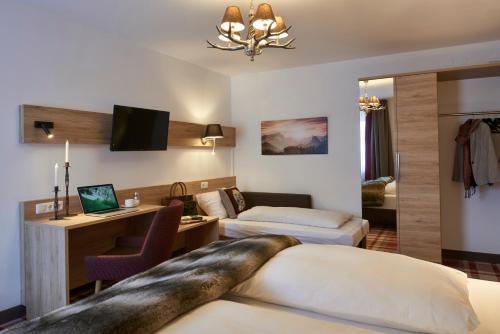 a hotel room with two beds and a desk at Hotel Weißbräu in Oberhaching