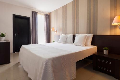um quarto com uma cama grande com lençóis brancos e almofadas em Blubay Apartments by ST Hotels em Il-Gżira
