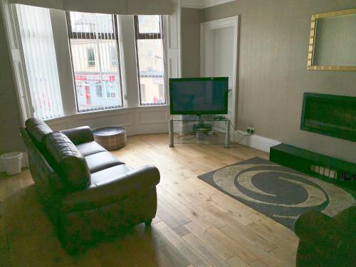 a living room with a couch and a television at The Village Tavern Apartment in Larkhall