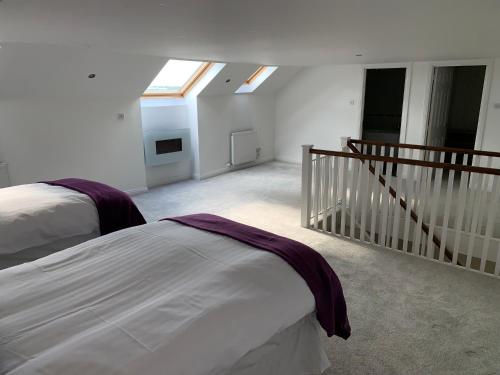 a bedroom with two beds and a staircase with skylights at The Village Tavern Apartment in Larkhall