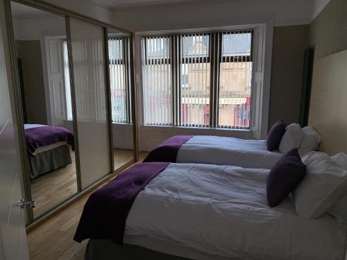 a bedroom with two beds and a large window at The Village Tavern Apartment in Larkhall