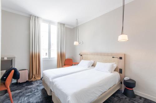 a hotel room with two beds and a chair at Hôtel Vendôme in Nice