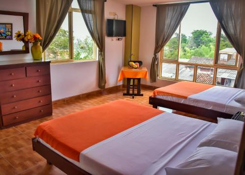 a bedroom with two beds and a dresser and windows at Hotel La Terraza in Quimbaya
