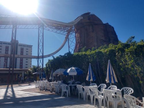 a group of tables and chairs with umbrellas and a roller coaster at PIAZZA DIROMA FLATS PARA TEMPORADA in Caldas Novas