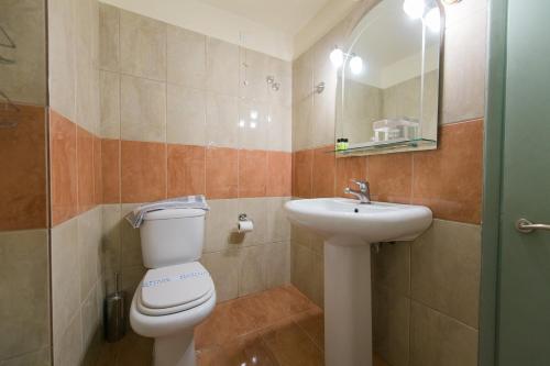 a bathroom with a toilet and a sink and a mirror at Plaz Hotel in Selianitika