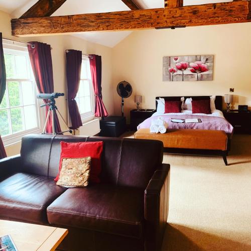 a bedroom with a bed and a leather couch at Bridge View Guest House in Ironbridge