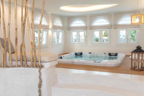 eine Whirlpool-Badewanne in einem Zimmer mit Fenstern in der Unterkunft Cycladic Islands Hotel & Spa in Agia Anna