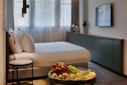 Una habitación con una cama y un bol de fruta en una mesa en The Muse Boutique Hotel Tel Aviv, en Tel Aviv