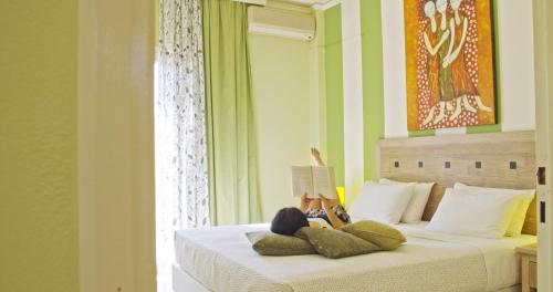 una camera con un letto con una persona sdraiata sopra di Waterlily Hotel Apartments a Kalathas