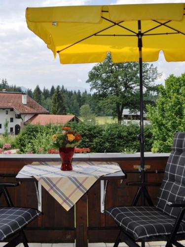 a table with a yellow umbrella and two chairs at Gästehäuser Schwemmbauer in Reit im Winkl