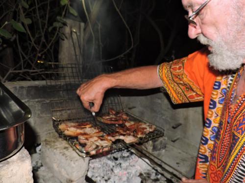 a man is cooking food on a grill at Kruger Inn Backpackers in Marloth Park