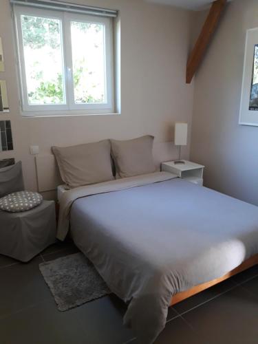 Un dormitorio con una gran cama blanca y una ventana en Chalet Rocamadour, en Lanzac