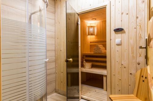 y baño de madera con ducha y puerta de cristal. en Domy Sywarne z Sauną i widokiem na góry, en Kościelisko