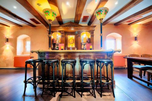 a bar with four stools in a room at Welcome Hotel Bad Arolsen in Bad Arolsen
