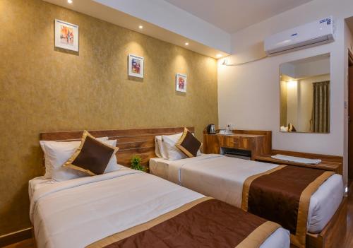 a hotel room with two beds and a mirror at Kensington Suites in Bengaluru