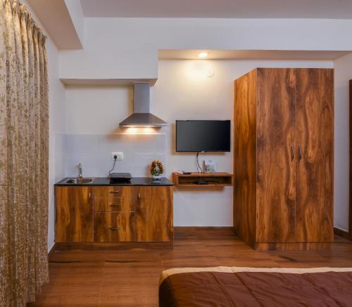 バンガロールにあるKensington Suitesの大きな木製キャビネットとテレビが備わる客室です。