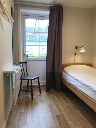 a bedroom with a bed and a chair and a window at Ölands Yoga Studio & Islandshästar, Stugor & Rum in Mörbylånga