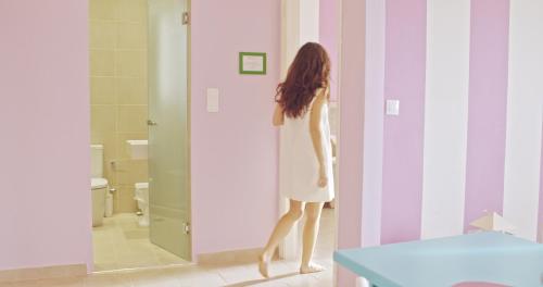 a woman in a white dress standing in a bathroom at Waterlily Hotel Apartments in Kalathas