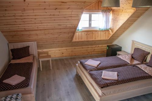 a attic room with two beds and a window at Kaimo turizmo sodyba "Ąžuola" in Vainutas