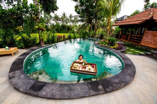 a person in a boat in a swimming pool at Puri Kobot in Ubud