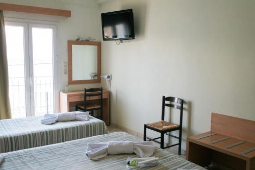 a bedroom with two beds and a television on the wall at Plaz Hotel in Selianitika