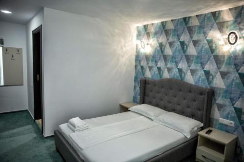 a bedroom with a bed and a wall with at Pensiunea Beny in Târgu Jiu