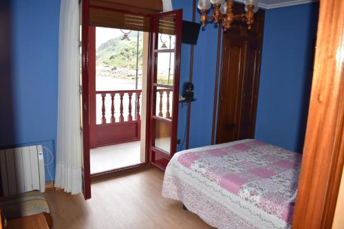 a bedroom with a bed and a door to a balcony at Hotel Imperial in Tazones