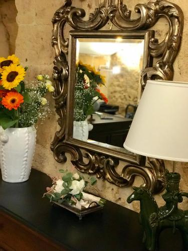a mirror on a table with a lamp and flowers at Ponticelli B&B Boutique in Gravina in Puglia