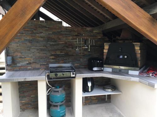 an outdoor kitchen with a grill and a stove at Le charme d'othe in Bellechaume