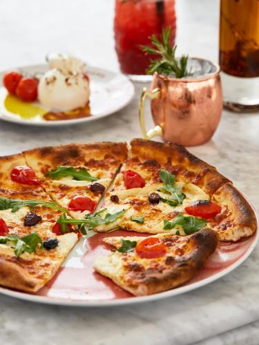 a pizza sitting on a plate on a table at Mama Shelter Toulouse in Toulouse
