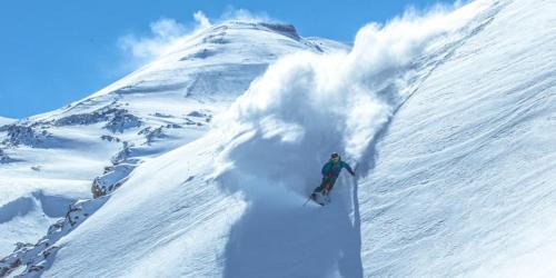 a person riding a snowboard down a snow covered mountain at Departamentos Exclusivos Termas de Chillán in Nevados de Chillan