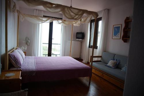 ein Schlafzimmer mit einem Bett, einer Couch und einem Fenster in der Unterkunft Seaside Vila in Platanitis