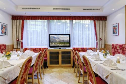 a dining room with tables and chairs and a television at Hotel Finkenbergerhof in Finkenberg