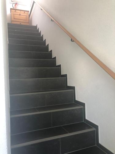 un escalier avec des marches noires et une porte en bois dans l'établissement Haus Estrella, à Radolfzell am Bodensee