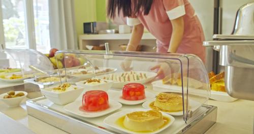 a display case with desserts on plates on a counter at Waterlily Hotel Apartments in Kalathas