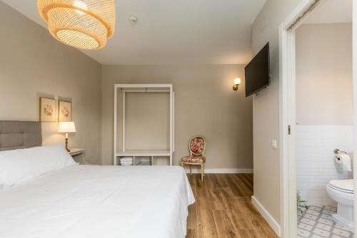 a bedroom with a white bed and a toilet at Alquería Calatrava B&B in Burriana