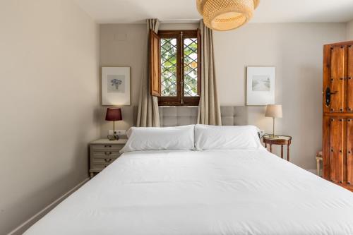 a bedroom with a large white bed and a window at Alquería Calatrava B&B in Burriana