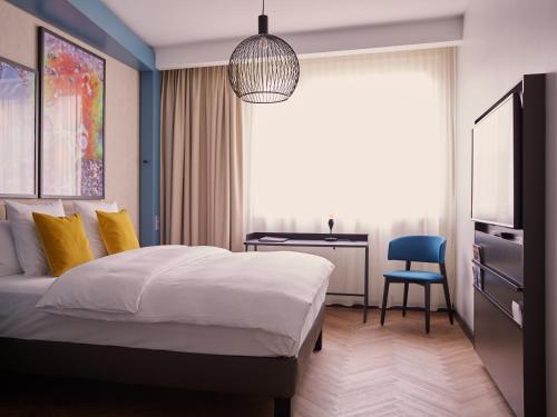 a bedroom with a bed and a desk and a chair at Hotel Mondial am Dom Cologne MGallery in Cologne